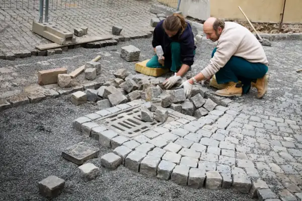 Stratenmakers zetten keien met de hand rond een put, bestrating leggen in Amsterdam