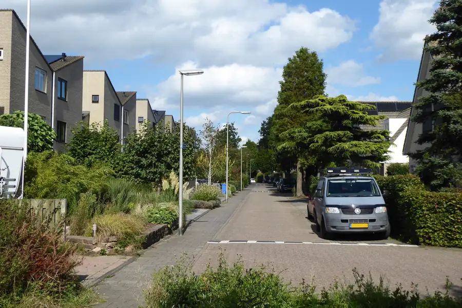 Nederlandse woonstraat met klinkerbestrating, stoep en voortuinen waar een uitweg naar een oprit zou komen