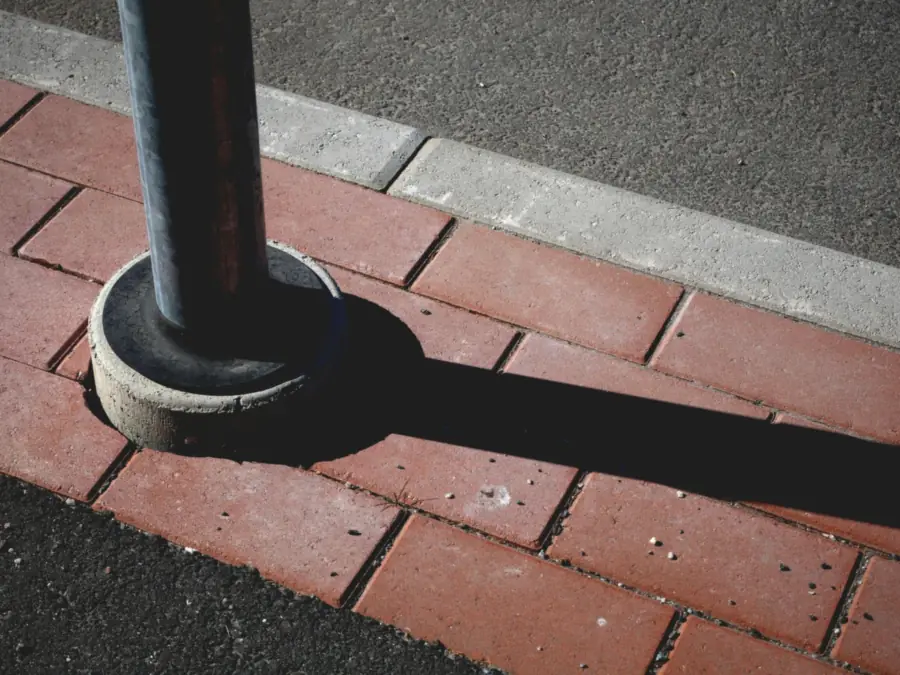 Rode betonklinkers met een grijze opsluitband langs het asfalt, detail van de randafwerking bij een oprit aanleggen in Amsterdam